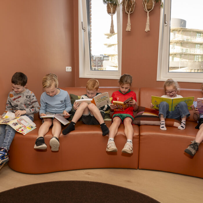 kinderen lezen boek op de bank bij bso 2pinguins in naaldwijk kinderopvang 2samen
